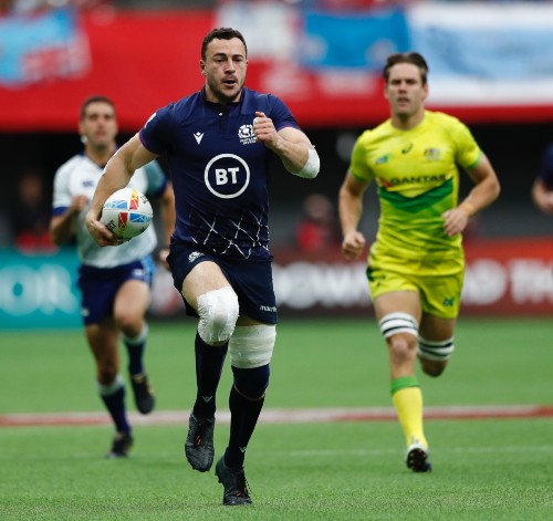 Jamie Farndale in blue strip running with rugby ball pursued by opponent in yellow