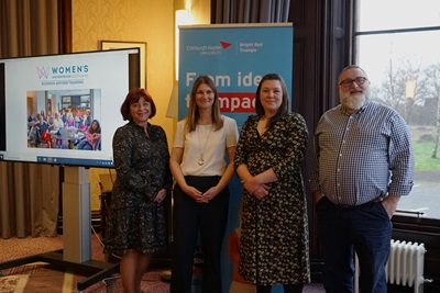 Four people posing in front of a Bright Red Triangle poster