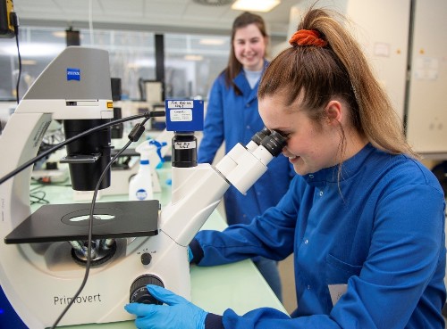 close up of a female student working on a microscope