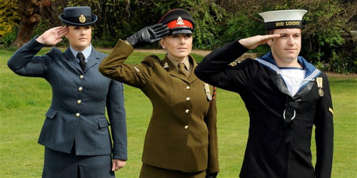 Line up of saluting members of armed forces - one RAF, one soldier, one sailor