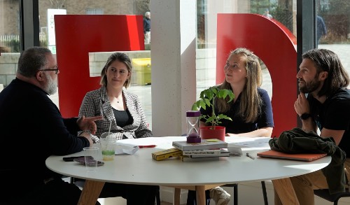 Two men and two women sitting chatting at a round table