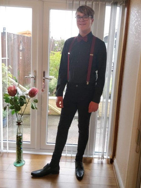 Calum Turner, tall teenage boy, dressed in dark clothing in front of window in house 