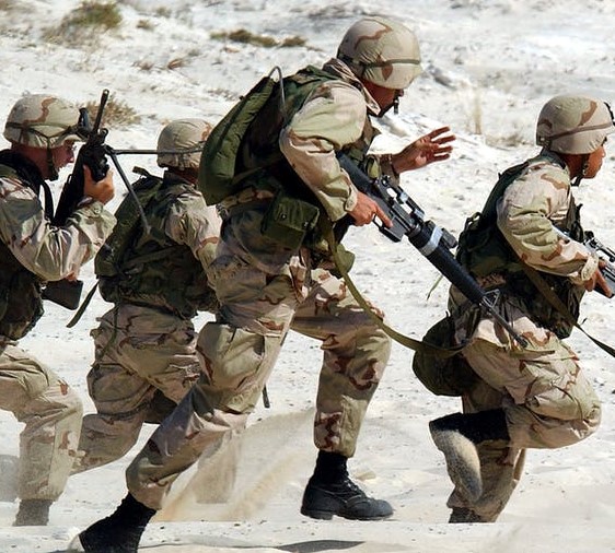 Soldiers running in combat gear in a desert setting