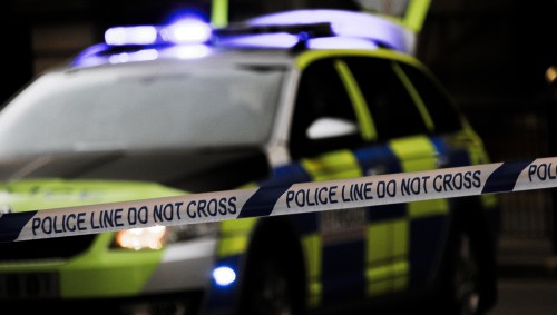 Police tape, with a police car in the background