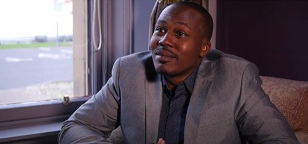 Davidson Ishmael, in light-coloured suit jacket and dark shirt, seated next to a window