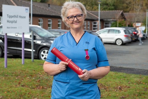 Ellie Lamb in nursing uniform holding graduation scroll outside Tippethill Hospital in Armadale