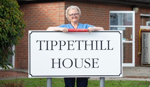 Ellie Lamb with graduation scroll at sign for Tippethill Hospital in Armadale