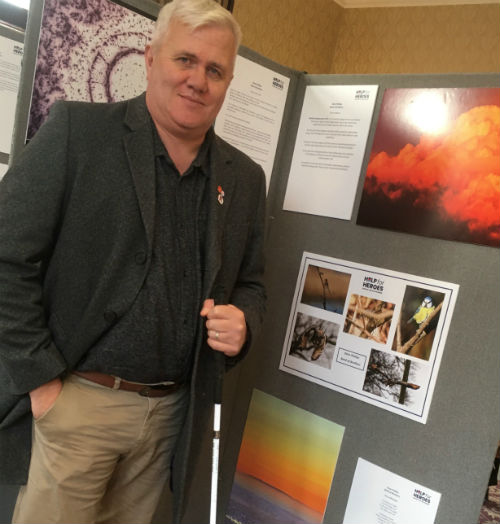 Dave Phillips beside a display board with his poems and other art