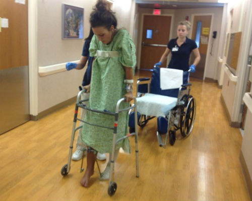 Kasey Johnson with a walking frame in a hospital corridor 