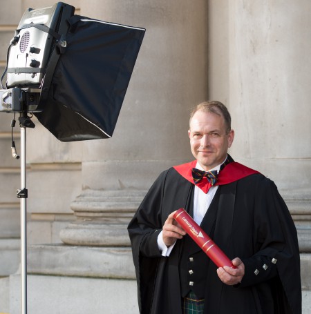 Matt Jones posing with a scroll at his graduation