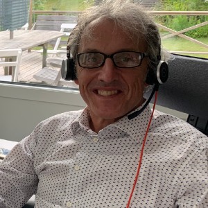 Head and shoulders of Simon Davies, bespectacled and wearing white shirt, smiling, sitting in the office