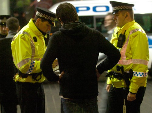 Police officers speaking to a man standing on the street at night