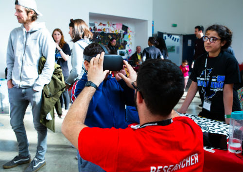 Researcher taking photo of child in busy community centre