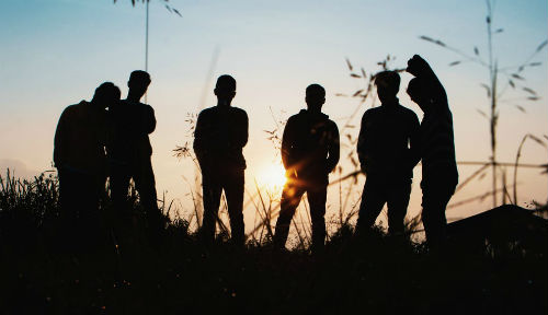 Six young people in silhouette in an outdoor setting