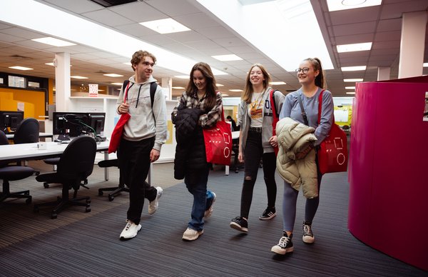 Four students walking through the LRC at Merchiston campus during an Edinburgh Napier Open Day. 