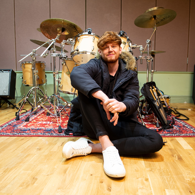 Image of Jordan Harvey in front of drum kit at Edinburgh Napier University 