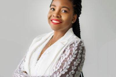 Professional image of Dr Afiya Holder with their arms folded, smiling