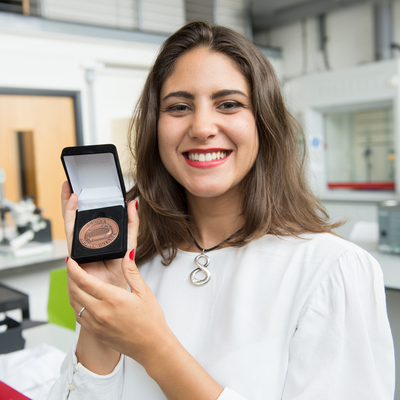 Andrea smiling whilst holding up the IET prize to the camera