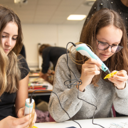 Students using handheld tools to work on a STEM project in a laboratory setting.