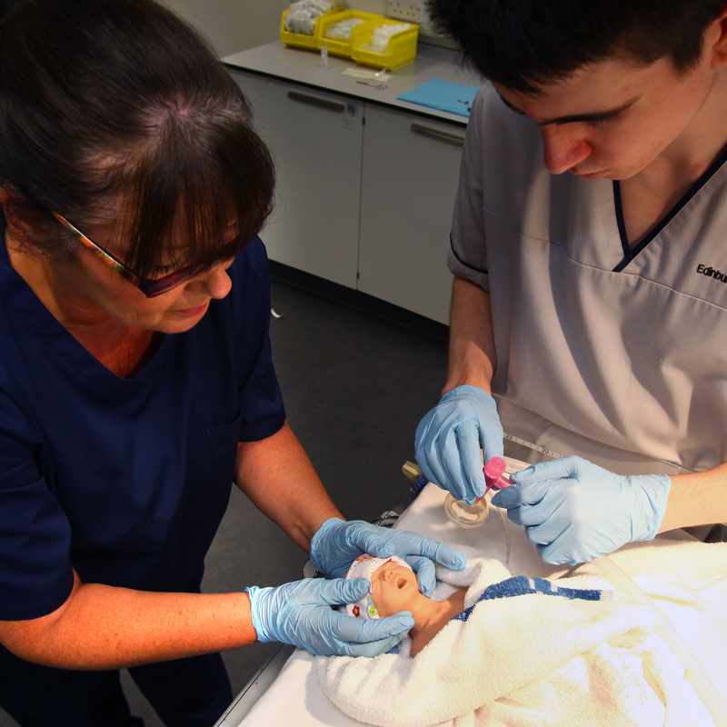 Nursing student with mentor, working on a n infant mannequin.