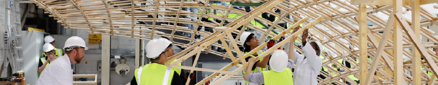 Students assembling a large timber structure in a construction lab