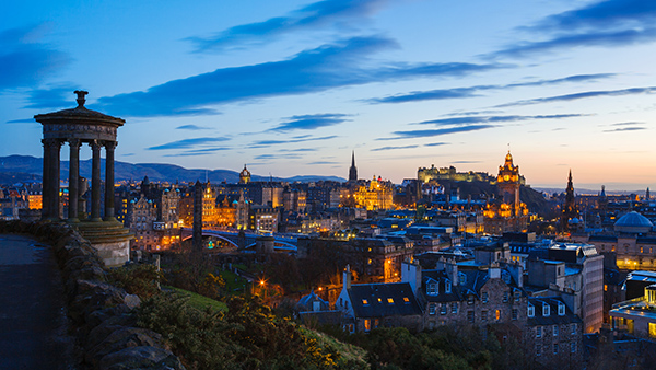 Dugald Stewart Monument on Calton Hill at night, with the Edinburgh cityscape behind