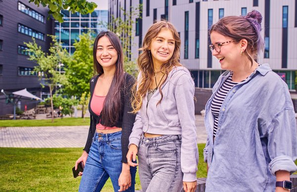A group photo of Edinburgh Napier students outside the main building at Sighthill campus on a sunny day. 
