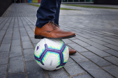 Dress shoe on top of a football. 