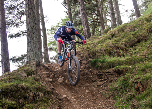 Mountain biker going down a steep trail at Glentress forest. 