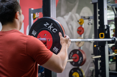 Person placing a weight plate on a bar in the Engage Gym at Edinburgh Napier's Sighthill campus.