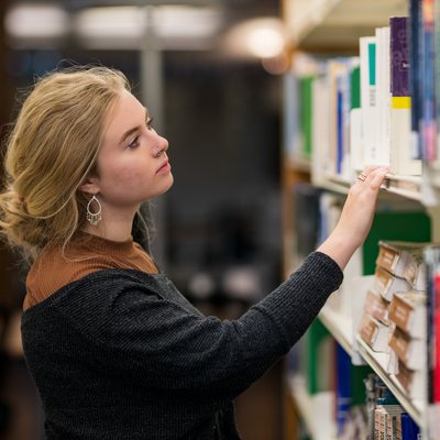 student looking through books in library