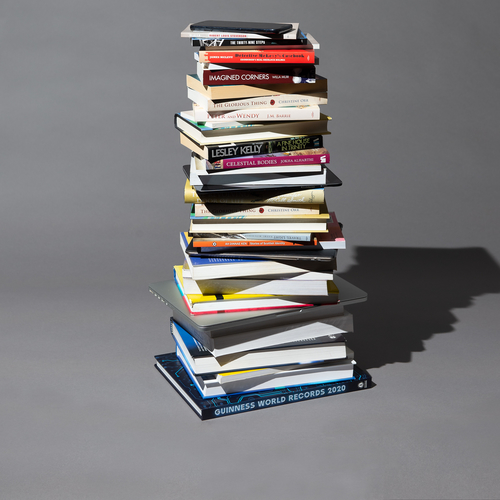 Books stacked up on table with mobile phone on top